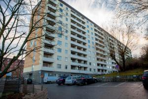 een groot appartementencomplex met auto's geparkeerd op een parkeerplaats bij ApartDirect Solna in Solna