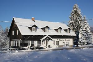 a large black and white house in the snow at Penzion Semerink in Janov nad Nisou