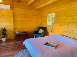 a bedroom with a bed and a blue chair at Chalet Loda cosy spa privé in Roussayrolles