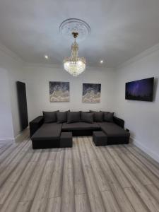a living room with a black couch and a chandelier at Eastend Apartments in London