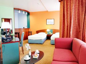 a hotel room with two beds and a red couch at Al Diar Dana Hotel in Abu Dhabi