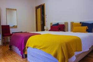 a bedroom with a large bed with colorful pillows at Casa de Campo Vale do Ceira in Góis