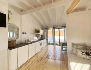 cocina con armarios blancos y suelo de madera en Casa Aquamarine, en Barcelona