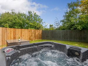 a hot tub in a backyard with a fence at Alder Lodge in Mattishall