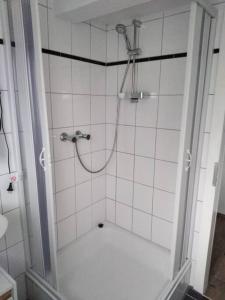 La salle de bains est pourvue d'une douche et de carrelage blanc. dans l'établissement Wohnung im Grünen in Olsberg, à Olsberg