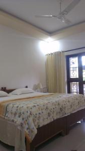 um quarto com uma cama grande e uma colcha floral em Alba Rooms Palolem Rosebuds em Palolem