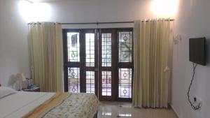 a bedroom with a bed and a sliding glass door at Alba Rooms Palolem Rosebuds in Palolem