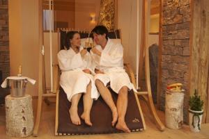 a man and woman sitting in a chair in a room at Hotel Alpenwelt Superior in Flachau