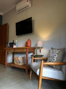 a living room with a chair and a tv on the wall at Pousada Villa Paraizo in Ribeirão Claro