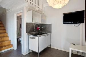 una cucina con lavandino e una TV a parete di Camping Grande Italia Chalet Mare 2 a Chioggia