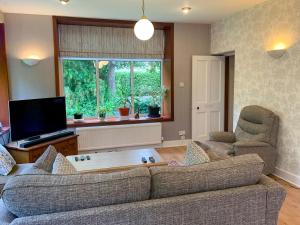 a living room with a couch and a tv at The Coyles - Uk31466 in Ballater