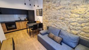 salon z niebieską kanapą i kamienną ścianą w obiekcie Szczytowa Kamienica Apartamenty Blisko Centrum w mieście Częstochowa