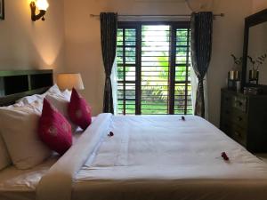 a bedroom with a large white bed with pink pillows at Villa Wodeyarmutt Tropical luxury living in Sringeri