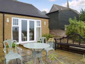 a patio with a table and chairs and a bench at Studio Quercus in Todenham