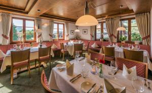 ein Restaurant mit weißen Tischen, Stühlen und Fenstern in der Unterkunft Hotel Gasthaus Mosers Blume in Haslach im Kinzigtal
