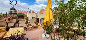 eine Terrasse mit Stühlen, Tischen und einem gelben Sonnenschirm in der Unterkunft Abelia Traditional Riad - All Inclusive - 2023 traveler's Choice Award in Marrakesch