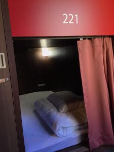 a small bed in a room with a window at ゲストハウス長岡街宿 in Nagaoka