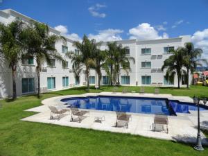 a large building with a pool and chairs in a yard at Hotel Real de Minas Bajio in Le&oacute;n