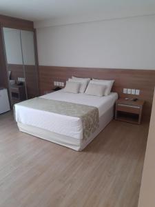 a bedroom with a large bed with white sheets and pillows at Vista Azul Apart Hotel - Vista Pinheiros in Domingos Martins