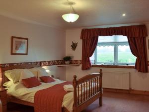 a bedroom with a bed with red curtains and a window at West Tannacrieff in Stewarton