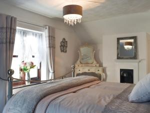 a bedroom with a bed and a window and a chandelier at Wilma Cottage in Geldeston