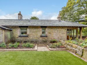 an old stone house with a garden in front of it at Gadley Cottage - Uk31490 in Buxton