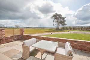 un patio con tavolo, sedie e vista su un campo di Orchard View Cottage a Yedingham
