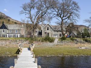 a wooden bridge over a river with a house at Lochearnside Lodge in Saint Fillans