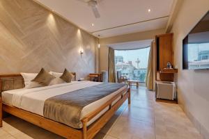 a bedroom with a large bed and a television at Artilla Inn in Ahmedabad