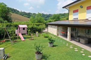 einen Hinterhof mit einem Spielplatz und einem Haus in der Unterkunft App in Villa con Piscina - 45 min Venezia - Zona Unesco in San Pietro di Feletto