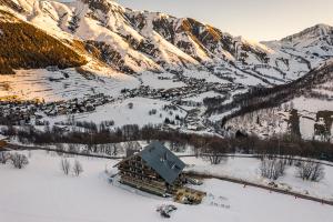 un lodge dans la neige en face d'une montagne dans l'établissement Les Cèdres - Hôtel - Restaurants - Spa, à Saint-Sorlin-dʼArves