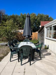 - une table avec un parasol et des chaises sur la terrasse dans l'établissement Sanvent, à Fort-Mahon-Plage