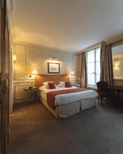 パリにあるホテル ドゥ リュニベルシテの大きなベッドと窓が備わるホテルルームです。