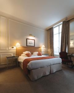 パリにあるホテル ドゥ リュニベルシテの大きなベッドと窓が備わるホテルルームです。