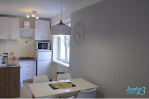 a kitchen with a table and a clock on the wall at Apartament Sapphire Time 3 in Łódź