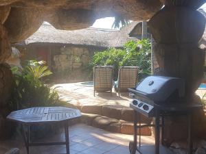 a grill in a patio with a table and chairs at Bushmans Rock in Pretoria
