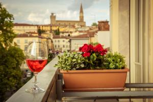 una copa de vino sentada en un balcón con una maceta de flores en La Terrazza, en Arezzo
