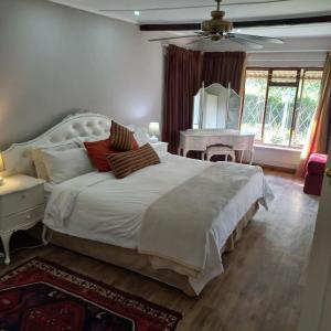 a bedroom with a large white bed and a mirror at Rosedale Self Catering Cottage with pool and large entertainment BBQ area in Henburg Park