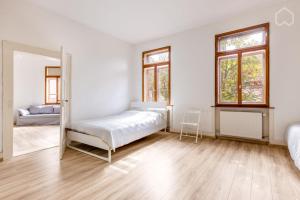 a white bedroom with a bed and two windows at Historic 4 Rooms in Mannheim