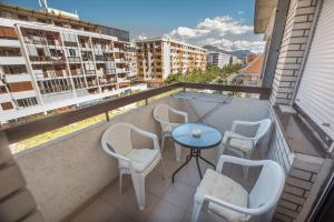 a balcony with a blue table and chairs and buildings at Apartman Vukcevic in Podgorica