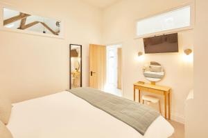 ein weißes Schlafzimmer mit einem Bett und einem Fernseher in der Unterkunft The Stables Cottage in Yedingham