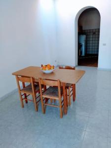una mesa de madera y sillas con un bol de fruta. en Casa Centineo en Barcellona-Pozzo di Gotto