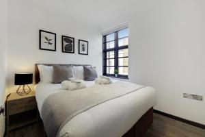 a bedroom with a large bed with two stuffed animals on it at Langdon Brooks Apartments in London