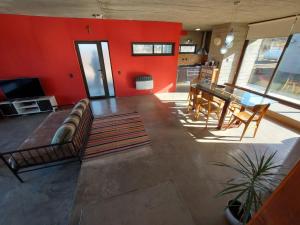 a living room with red walls and a couch and a table at SARA HOUSE LARGE in Santa Rosa de Calamuchita