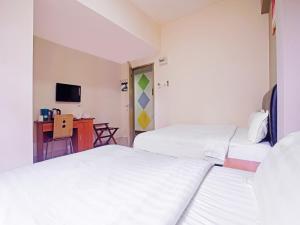 a hotel room with two beds and a desk at Super OYO 90516 Hotel Night Queen salak Tinggi in Sepang