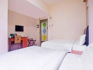 a hotel room with two beds and a desk at Super OYO 90516 Hotel Night Queen salak Tinggi in Sepang