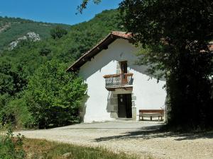 un pequeño edificio blanco con un banco delante en Araiztar, en Irañeta