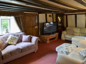 a living room with a couch and a tv at Tattlepot Farmhouse in Tivetshall Saint Margaret