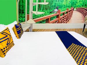 um quarto com uma cama com almofadas amarelas e azuis em OYO 91697 Nyaman Homestay Syariah em Pare