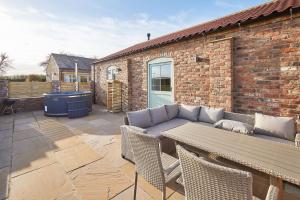 a patio with a couch and a table and chairs at Wold's View Cottage in Yedingham